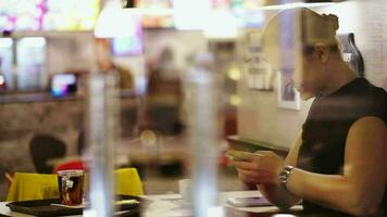 Jeune femme dans café en pensant plus de SMS et dactylographie il video