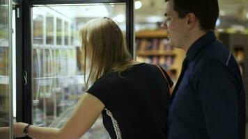 Mens en vrouw buying voorverpakking in bevroren sectie video