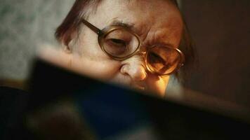 Senior woman in glasses with book at home video