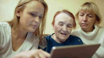 Woman with pad showing photos or video to her mother and grandmother