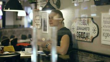 lächelnd Frau Tippen Botschaft auf ihr Smartphone Sitzung im das Cafe video