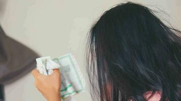 an Asian woman looks irritated and stressed while crumpling a piece of paper in her hands while in the room video