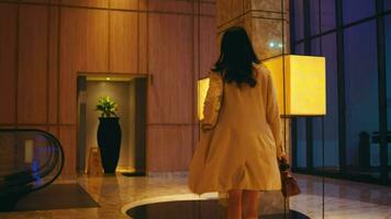 un asiático mujer con un bolso en su mano caminando en un lujoso hotel vestíbulo video
