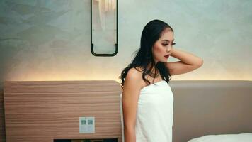 un asiático mujer pone en un blanco toalla después tomando un ducha en un lujoso hotel habitación video