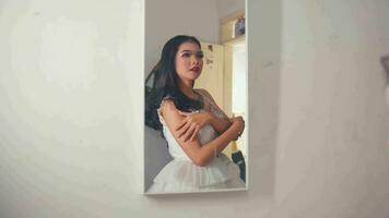 ein asiatisch Frau ist versuchen auf ein Hochzeit Kleid im Vorderseite von das Spiegel zum ihr Hochzeit video