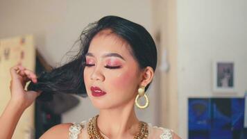 an Asian woman doing her makeup with brush and powder and lipstick in front of the mirror video