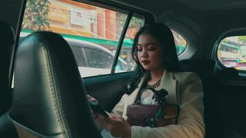 ett asiatisk kvinna är Sammanträde i de bil och kallelse henne vän för arbete video