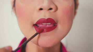 un asiático mujer haciendo su maquillaje con cepillo y polvo y lápiz labial en frente de el espejo video