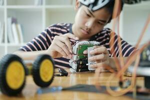 Asian teenager doing robot project in science classroom. technology of robotics programing and STEM education concept. photo