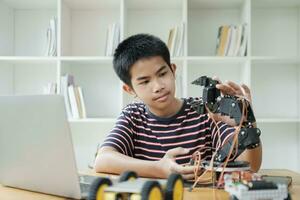 Asian teenager doing robot project in science classroom. technology of robotics programing and STEM education concept. photo