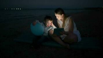 Mother and son with pad by the sea at night video