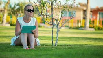 Beautiful woman sitting barefoot on a lawn video