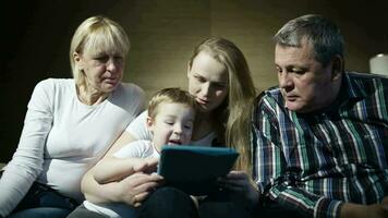 Family watching boy playing game on touchpad video