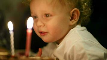 peu garçon soufflant en dehors deux bougies sur le sien anniversaire gâteau video