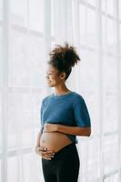 pregnant african american woman at home window white background photo