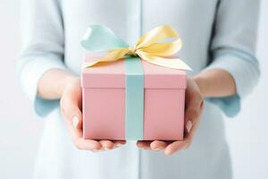 Hands holding a gift box with a bow. Neutral pastel background. photo