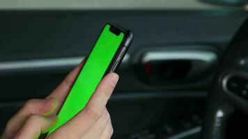 main en portant mobile téléphone vert écran à voiture, en utilisant téléphone à voiture, téléphone intelligent vert écran video