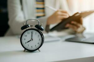 Alarm clock on the desk. Business hand using smartphone, laptop and tablet  working in modern office building or home photo