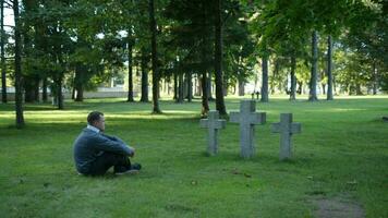 Man sitting mourning in front of three crosses video