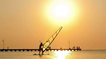 Silhouette of surfer at sunset passing by video