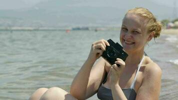 glimlachen vrouw nemen een foto Bij de kust met haar wijnoogst camera video