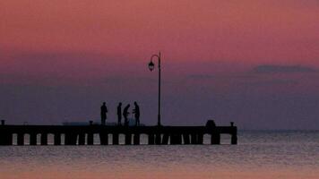 People on a pier at sunset video