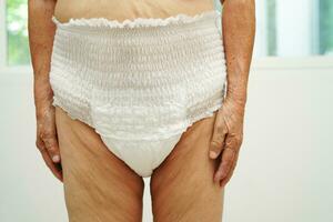 Asian senior woman patient wearing adult incontinence diaper pad in hospital. photo