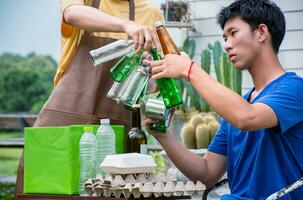 Young handsome asian gay couples are separating households, bottles, cans, trash, paper, egg tray, in front of their house, environment care and global warming concept. photo