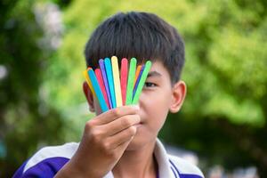 Ice-cream sticks in rainbow colours holding in hands of asian boy, soft and selective focus, concept for calling out all people to support LGBT events and campaigns around the world. photo