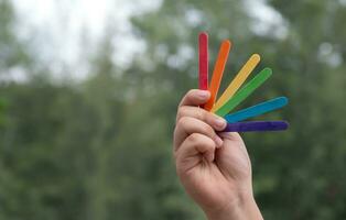 Ice-cream sticks in rainbow colours holding in hands of asian boy, soft and selective focus, concept for calling out all people to support LGBT events and campaigns around the world. photo