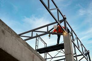 A Welders on risk areas. Steel roof truss welders are working on the roof structure with safety devices to prevent fall safety at the construction site. photo