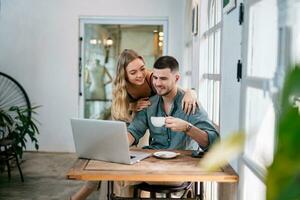 Happy young couple married spouse web surfing, making purchases online or booking flight tickets. The concept of couples sharing one idea together. photo