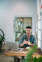 A male, Handsome Freelance man is using phone with laptop on table. freelance concept. photo