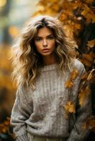 A woman in a cozy oversized sweater poses among fallen leaves showcasing the perfect blend of style and nature photo