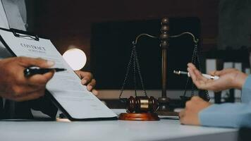 Business and lawyers discussing contract papers with brass scale on desk in office. Law, legal services, advice, justice and law concept picture with film grain effect video