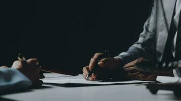 Business and lawyers discussing contract papers with brass scale on desk in office. Law, legal services, advice, justice and law concept picture with film grain effect video