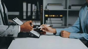 Business and lawyers discussing contract papers with brass scale on desk in office. Law, legal services, advice, justice and law concept picture with film grain effect video