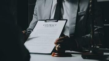 Business and lawyers discussing contract papers with brass scale on desk in office. Law, legal services, advice, justice and law concept picture with film grain effect video