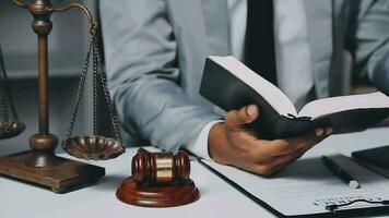 Business and lawyers discussing contract papers with brass scale on desk in office. Law, legal services, advice, justice and law concept picture with film grain effect video