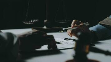 Business and lawyers discussing contract papers with brass scale on desk in office. Law, legal services, advice, justice and law concept picture with film grain effect video