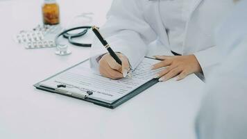 professionnel femelle médecin sourit et spectacles positif examen résultats à jeune, joyeux homme. beau, content gars avec des lunettes à médecins rendez-vous dans moderne Bureau de médical institution. video