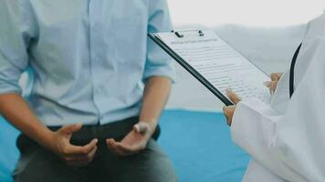 Professional female doctor smiles and shows positive examination results to young, joyful man. Handsome, happy guy with glasses at doctor's appointment in modern office of medical institution. video