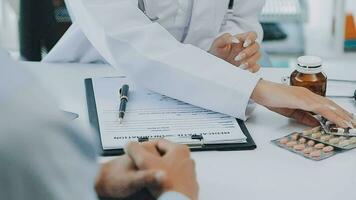 professionnel femelle médecin sourit et spectacles positif examen résultats à jeune, joyeux homme. beau, content gars avec des lunettes à médecins rendez-vous dans moderne Bureau de médical institution. video