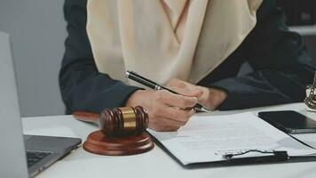 Business and lawyers discussing contract papers with brass scale on desk in office. Law, legal services, advice, justice and law concept picture with film grain effect video