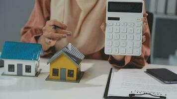 Female woman hands holding home model, small miniature white toy house. Mortgage property insurance dream moving home and real estate concept video