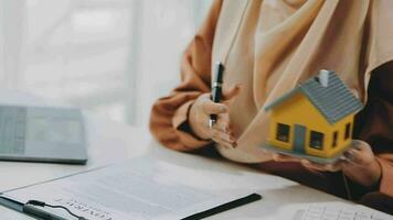 Female woman hands holding home model, small miniature white toy house. Mortgage property insurance dream moving home and real estate concept video