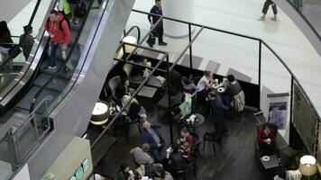Menschen Essen im das Cafe und gehen oben und Nieder auf das Rolltreppe video