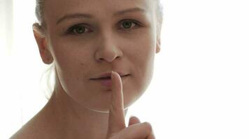 Portrait of young woman showing silence gesture video