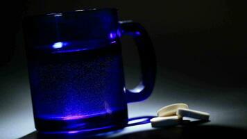 tavoletta dissoluzione nel un' blu bicchiere di acqua video