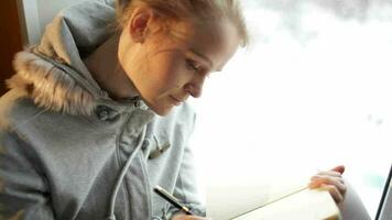 Jeune magnifique fille l'écriture dans sa journal et rêverie video